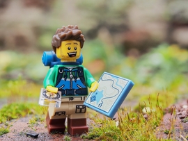 Lego-Männchen mit Kompass und Landkarte in der Natur