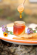 Honig tropft von einem Holzlöffel in ein Honigglas